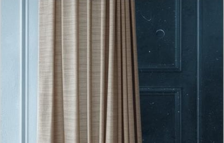 Pale curtains beside a weathered blue door with circular marks